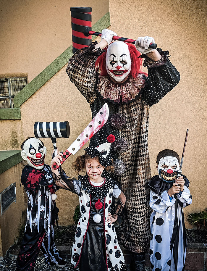 Group of kids and adult in scary clown Halloween costumes holding oversized props, showcasing creative kids Halloween costume ideas.
