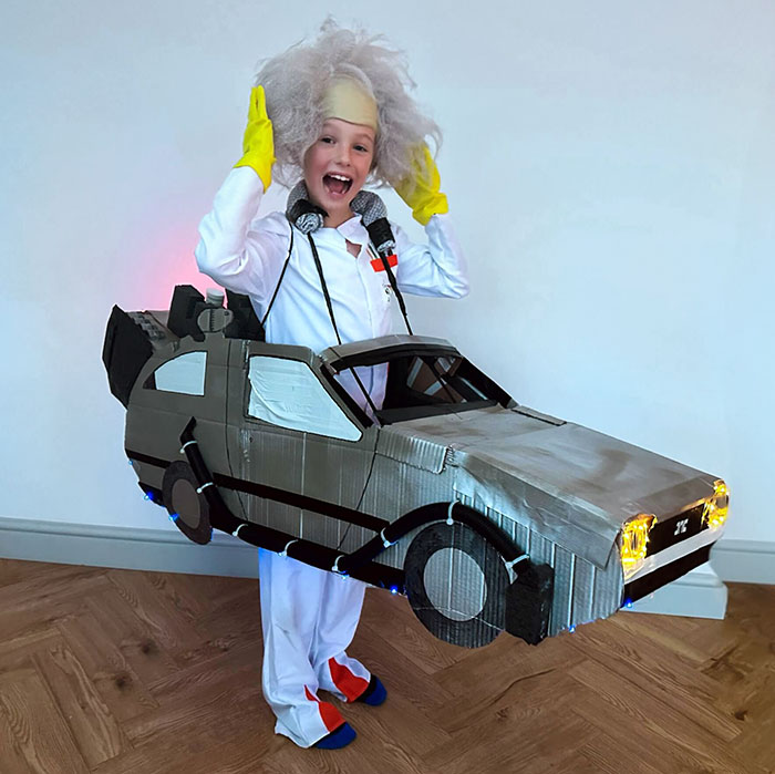 Child in creative Halloween costume with a homemade car and wild white wig, showcasing unique kids' Halloween costume ideas.