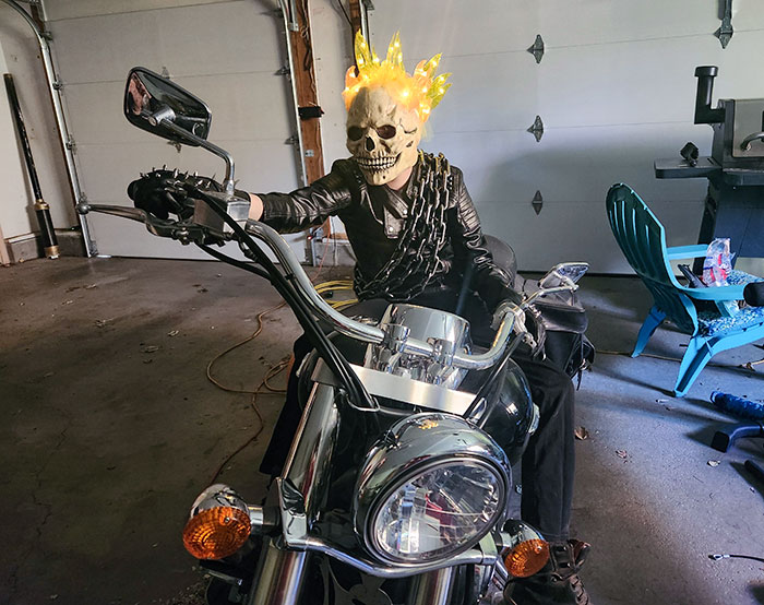 Child in Halloween costume with skull mask and fiery crown sitting on a motorcycle for kids Halloween costume ideas.