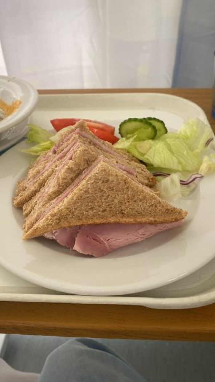 Ham sandwich with lettuce, cucumber, and tomato served on a tray as an example of hospital food from around the world