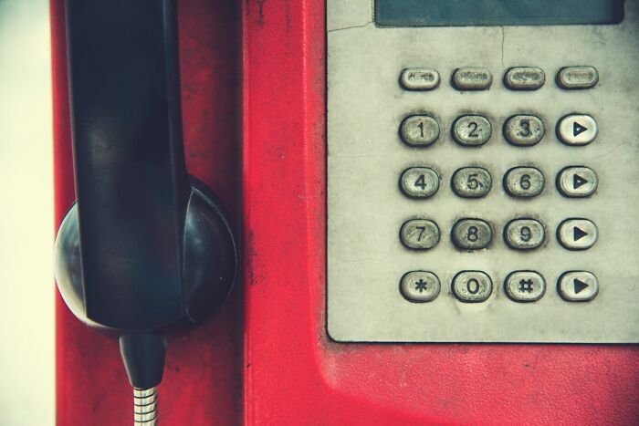 Close-up of a vintage red payphone with numeric keypad and black handset, illustrating mind-blowing coincidences concept.