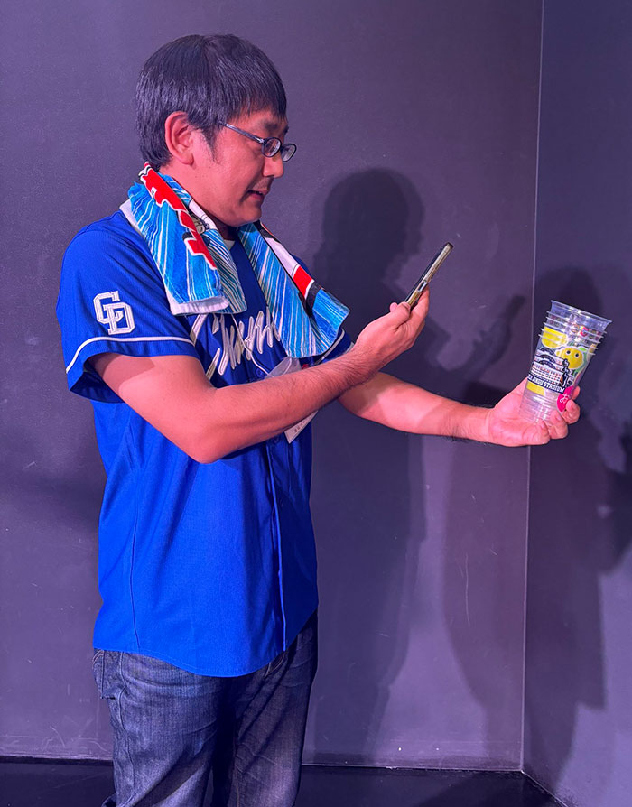 An Old Man Taking A Photo Of The Cup He Used At The Stadium