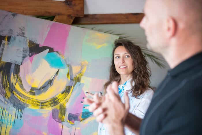 Woman explaining colorful abstract painting to a man, illustrating toxic relationships and warning signs to avoid red flags.