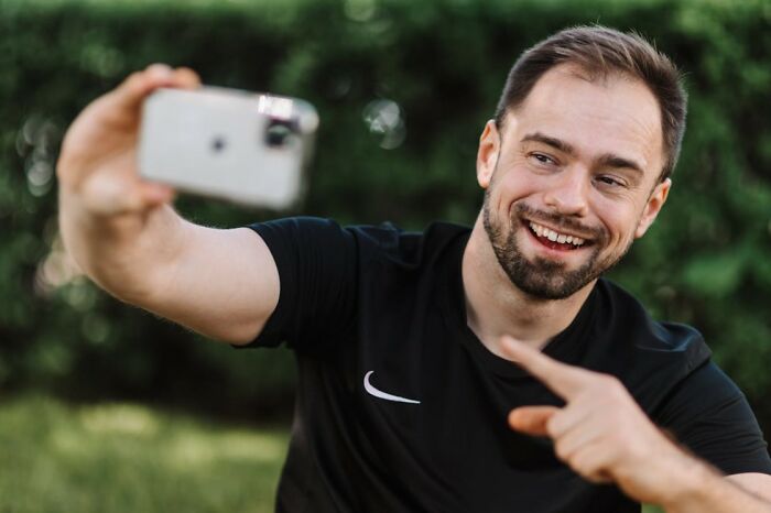 Man smiling and taking a selfie outdoors, highlighting toxic relationships and 24 red flags in social interactions.