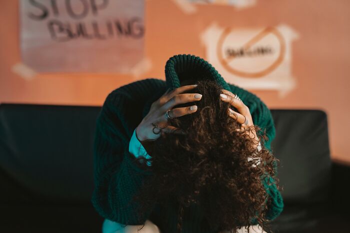 Person with curly hair holding their head in frustration, illustrating hatred after trying something once.