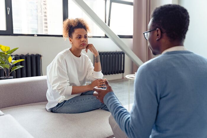 Two people in a serious conversation on a couch, depicting awareness of toxic relationships and red flags.