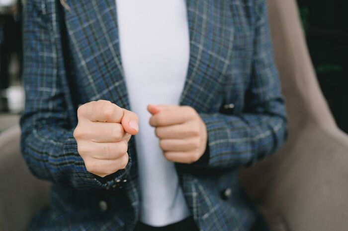 Person in plaid blazer clenching fists, symbolizing tension in toxic relationships and ignored red flags concept.