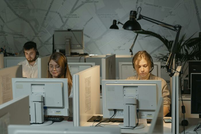 Three customer service agents working at computers in an office, illustrating people learning of their hatred after trying once.