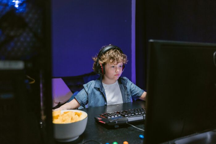 Young boy with headphones focused on computer screen, illustrating mind-blowing coincidences that seem impossible to be real.