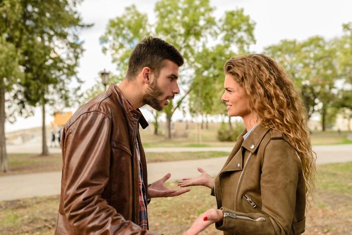 Man and woman arguing outdoors in a park, illustrating toxic relationships and red flags often ignored in conflicts.