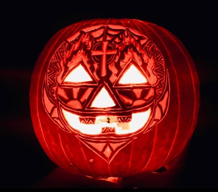 Intricately carved spooky pumpkin glowing in the dark showcasing quirky and charming pumpkin carvings design.