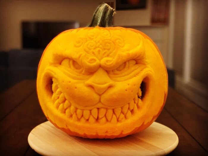 Intricately carved pumpkin featuring a spooky and quirky face, showcasing jaw-droppingly charming pumpkin carvings.