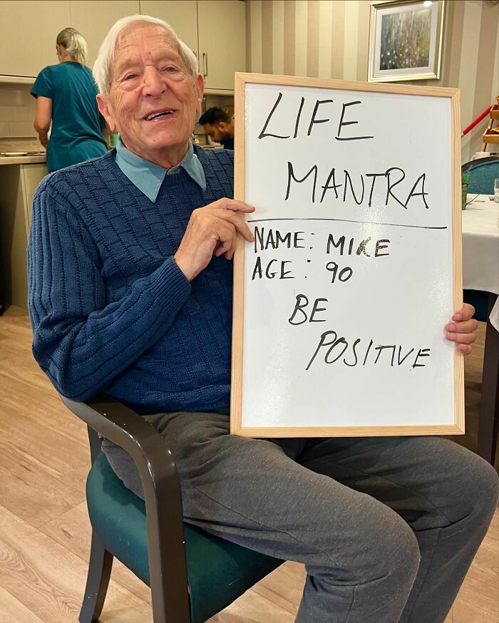 Elder man holding whiteboard with life advice be positive from elders doling out life advice Instagram page.