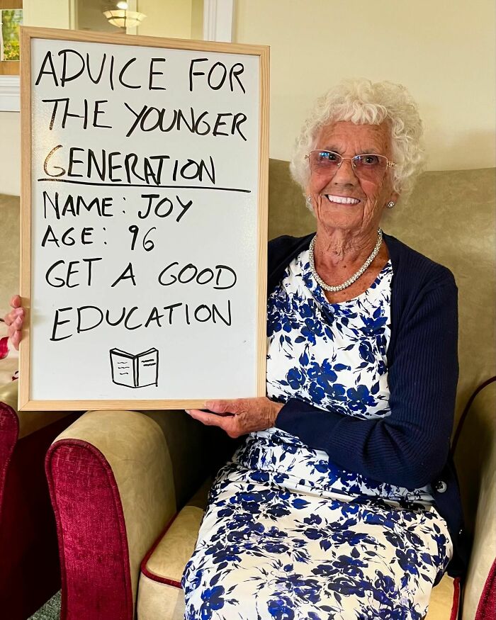 Elderly woman named Joy holding a whiteboard with life advice for the younger generation on an Instagram page.