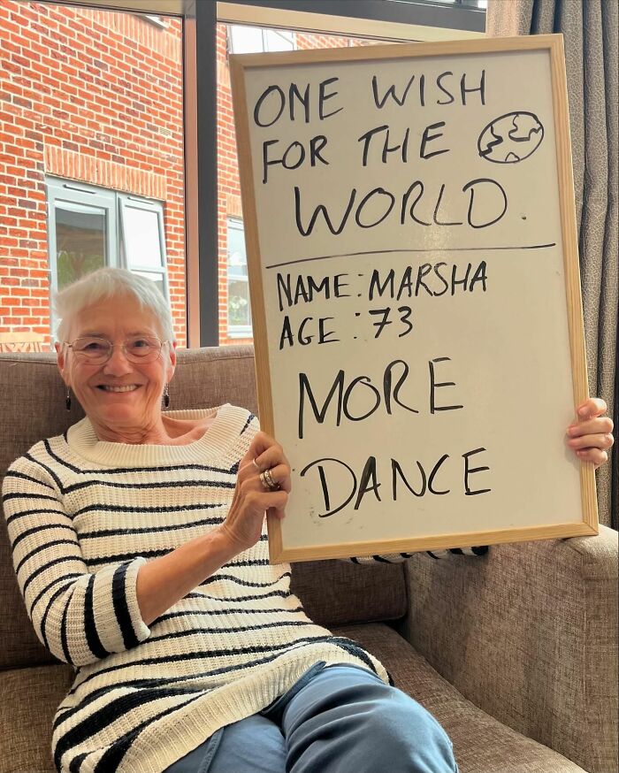 Elder woman smiling and holding a board with life advice featured on an Instagram page dedicated to elders sharing wisdom.