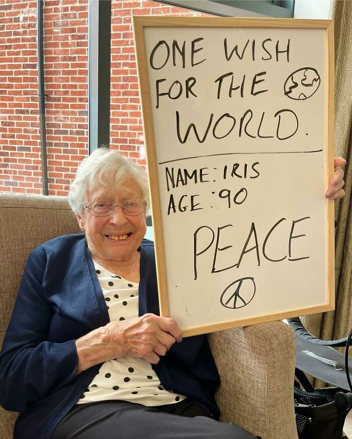 Elder smiling and holding a whiteboard with a life advice message about peace on an Instagram page dedicated to elders.