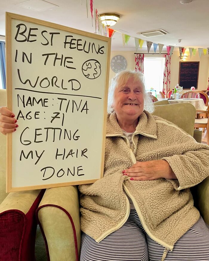 Elder smiling while holding board with life advice in cozy room, illustrating elders doling out life advice online.