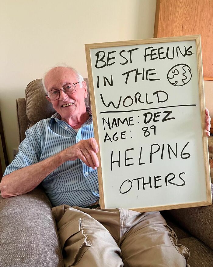 Elderly man on Instagram page sharing life advice holding a sign about the best feeling being helping others at age 89.
