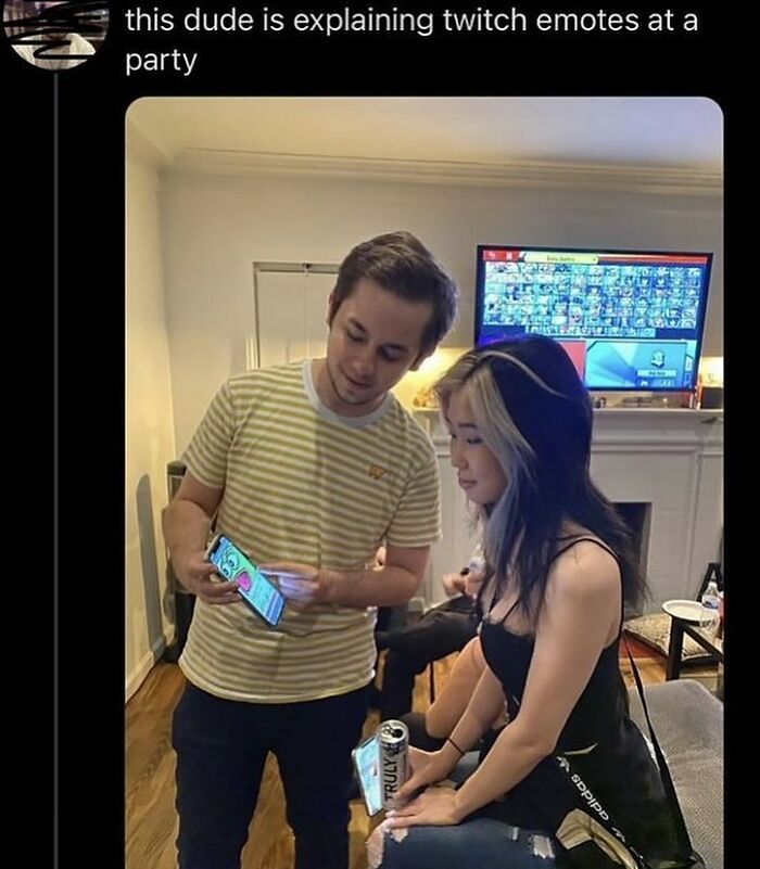 Two people indoors, one explaining something on a phone to the other, capturing a moment of sadistic memes humor.