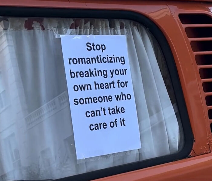 Wholesome message on a printed sign taped to a vintage vehicle window about love and self-care from the streets of London.