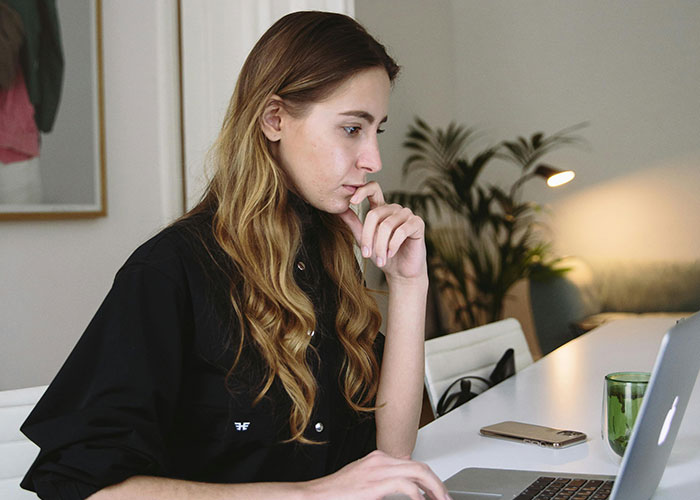 Young woman focused on laptop, illustrating indicators of a super smart person who hides intelligence well.