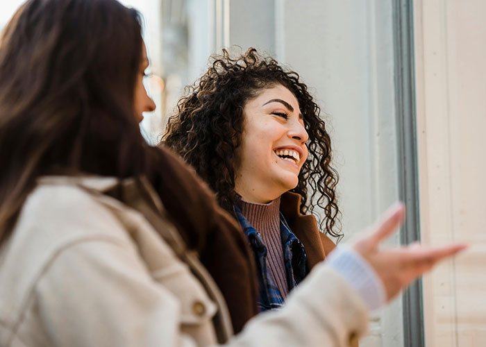 Two women smiling and talking casually, showing indicators that the person you’re talking to is super smart and hides it well.
