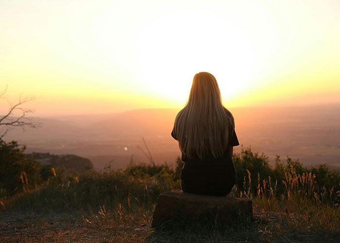 Person sitting alone at sunset, symbolizing deep thought and quiet intelligence, showing signs of being super smart and hiding it well.
