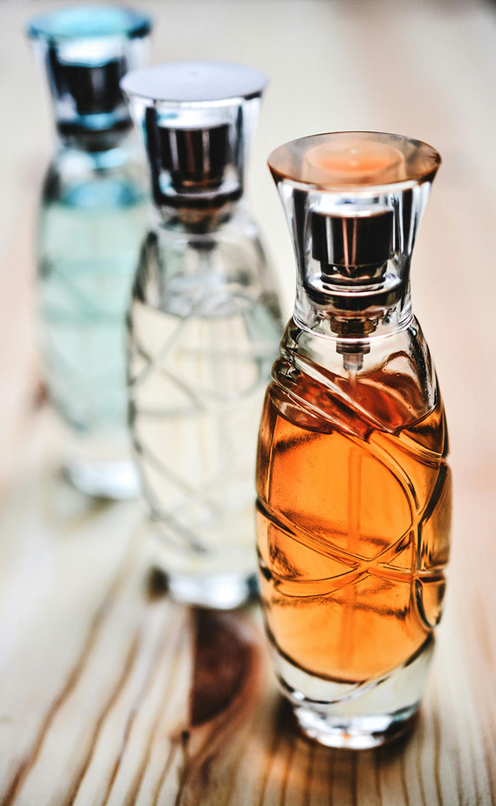 Three elegant perfume bottles in a row, each containing different colored liquids, representing a collection of high-end fragrances.