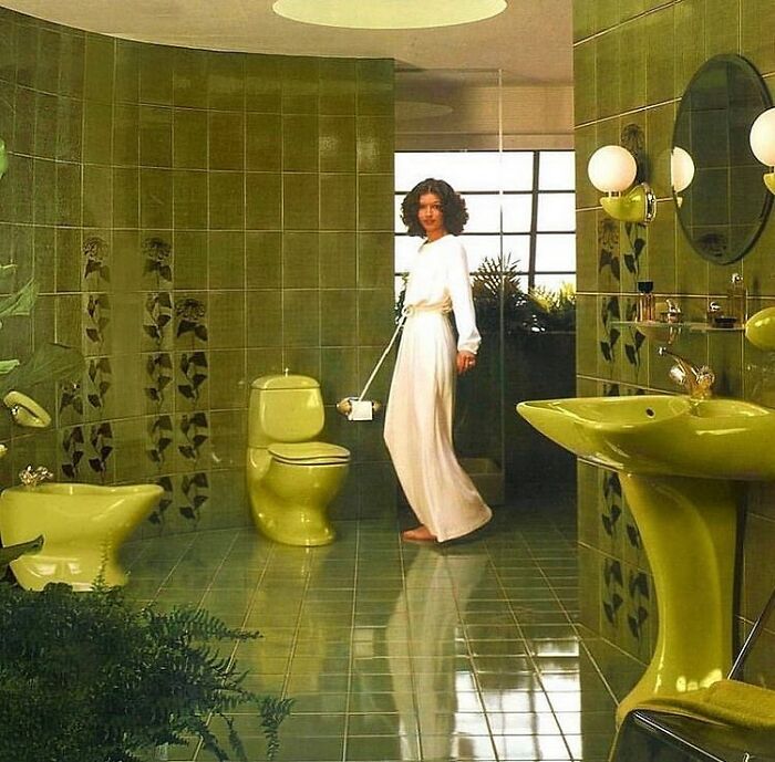 Woman in a vintage green bathroom showcasing captivating interiors from the 50s to 80s with unique retro design elements.