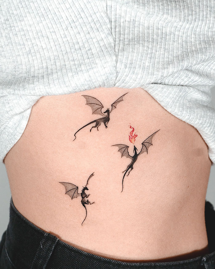 Three small dragon tattoos on the side, each with wings spread, one breathing fire.