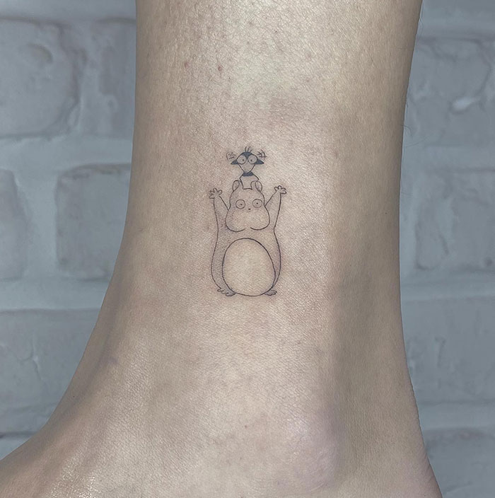 Small tattoo of a cartoon hippo with a bird on its head, on the ankle, showcasing minimalist design.