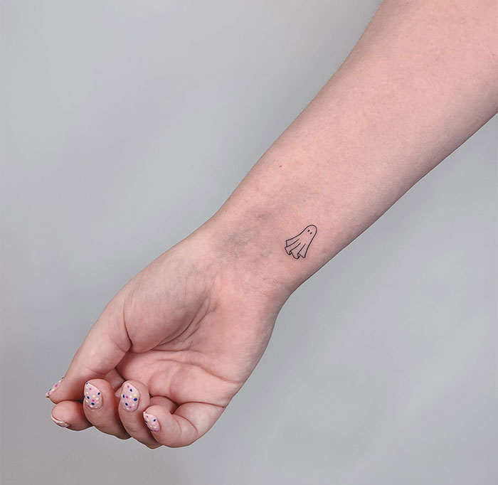 Minimalist ghost tattoo on the wrist, a small tattoo idea that packs a big punch.