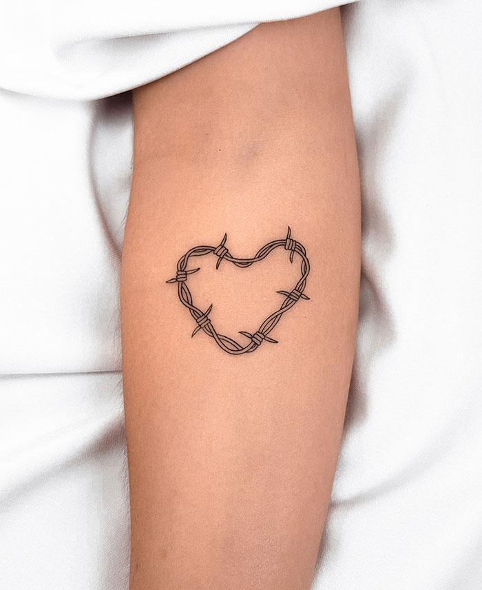 Barbed wire heart tattoo on forearm, showcasing small tattoo ideas.