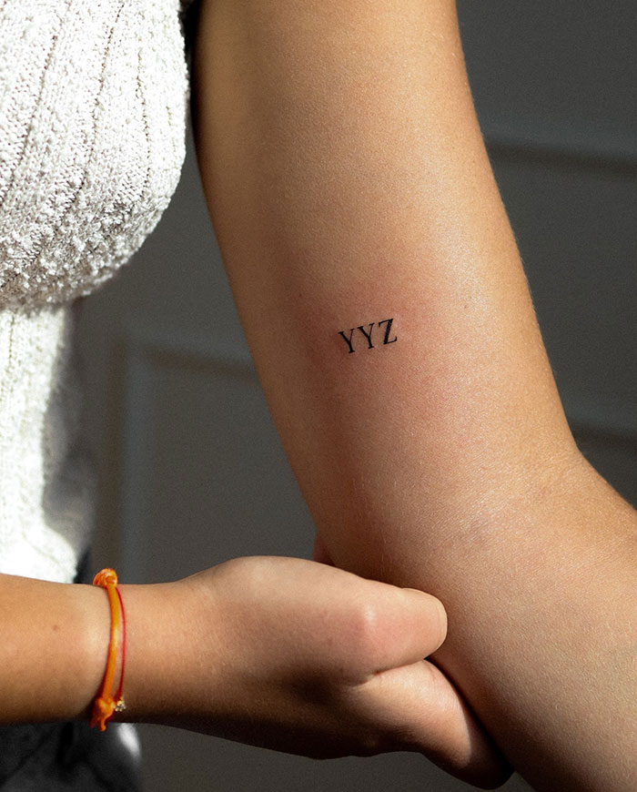 Arm displaying a small "YYZ" tattoo, exemplifying ideas for small tattoos that have a big impact.