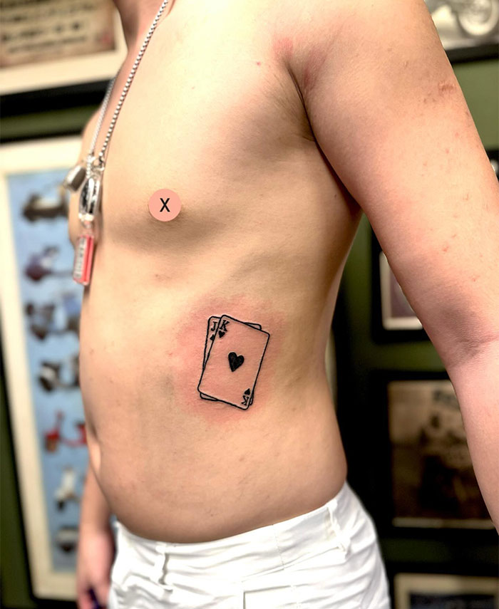 Small tattoo of a playing card with a heart symbol on a person's side.
