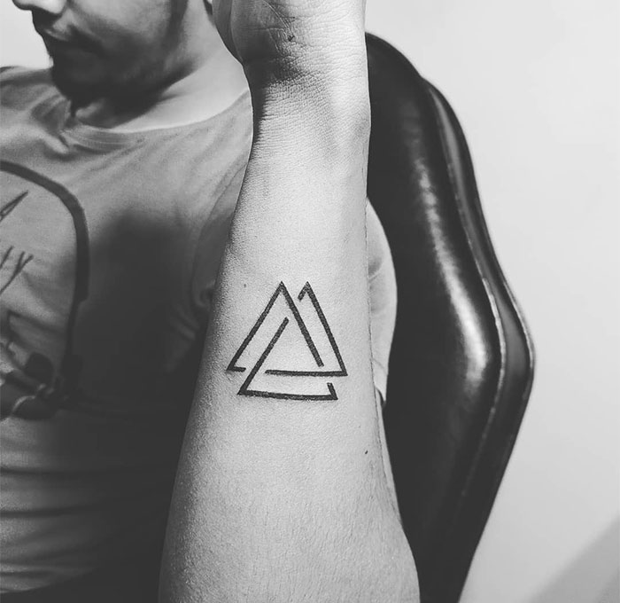 Minimalist triangle tattoo on forearm, showcasing small tattoo design with geometric style.