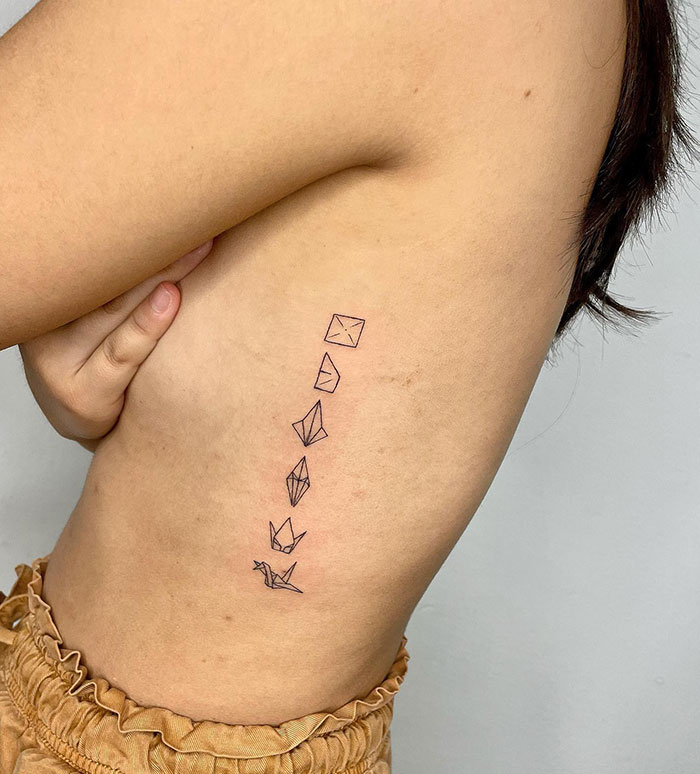 Side rib with small origami bird tattoo design, showcasing minimalist small tattoo ideas.