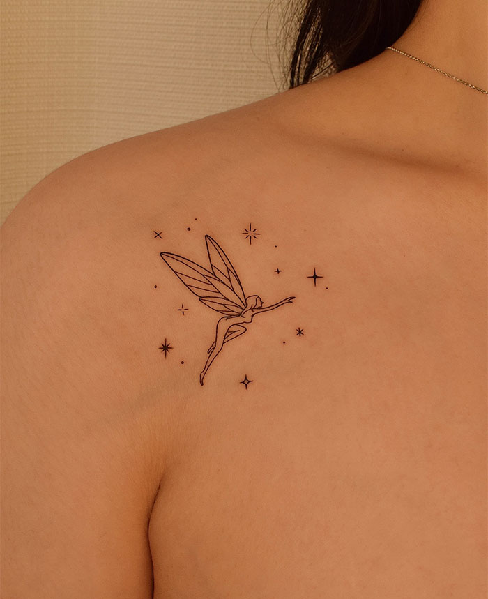 Fairy small tattoo on shoulder surrounded by stars, showcasing delicate linework and whimsical design inspiration.