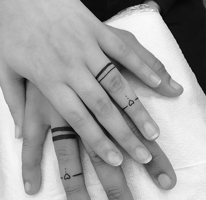 Close-up of small finger tattoos featuring minimalist lines and heart shapes, showcasing small tattoo ideas.