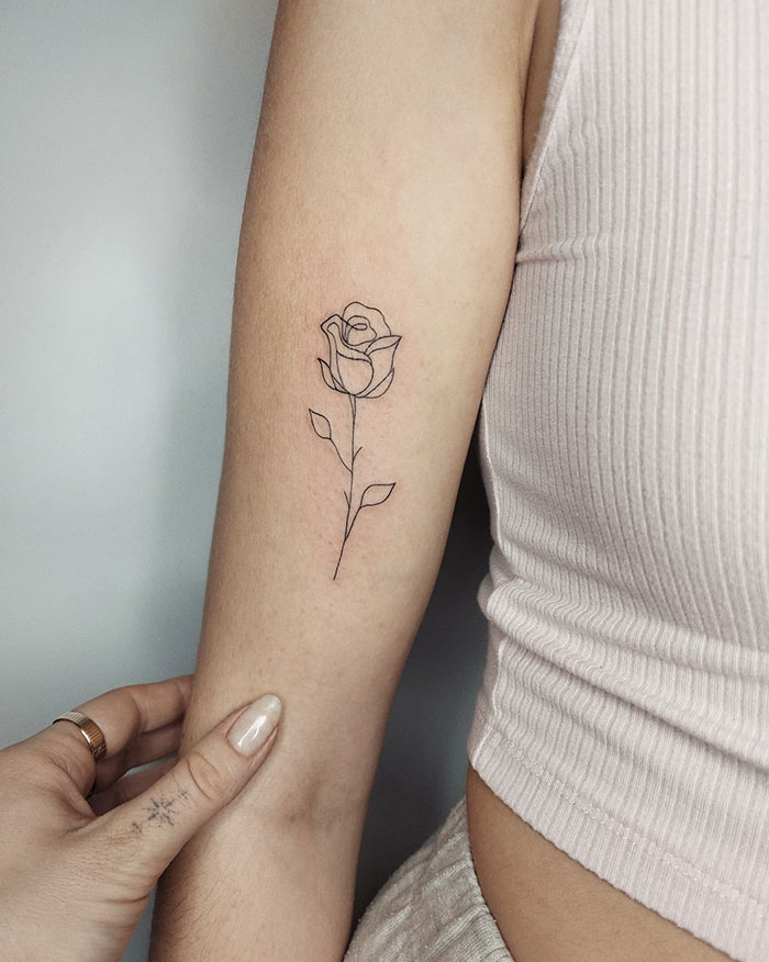 Minimalist rose small tattoo on forearm, showcasing delicate line work.