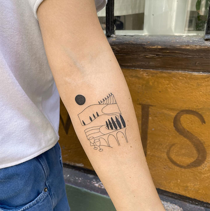 Minimalist small tattoo depicting a landscape with trees and geometric shapes on an arm.