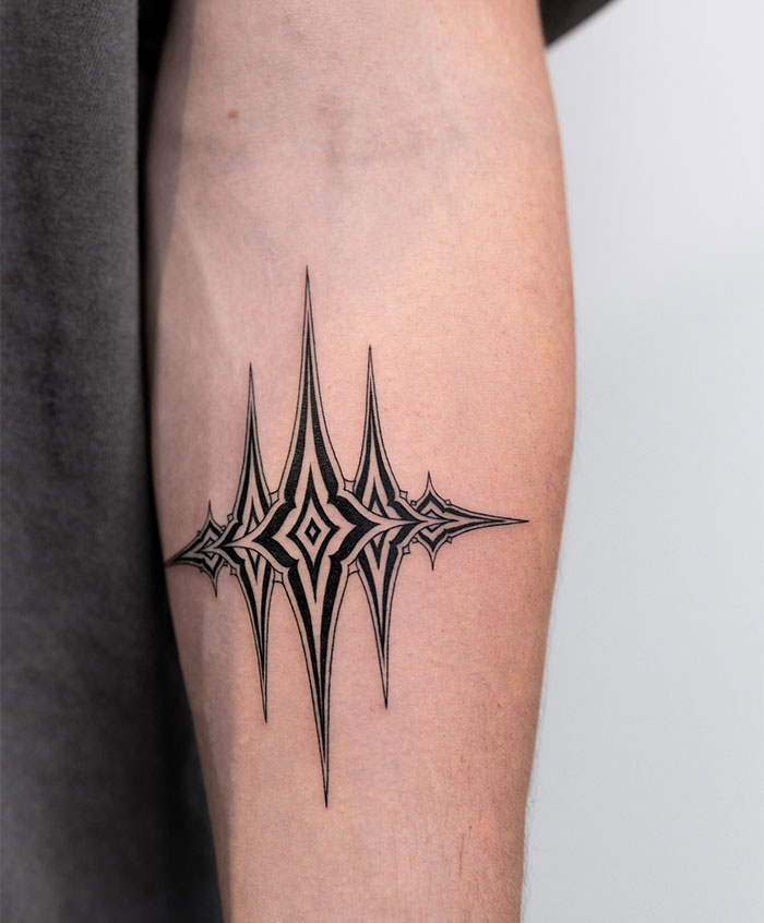 Abstract geometric small tattoo design on forearm, showcasing intricate lines and patterns.