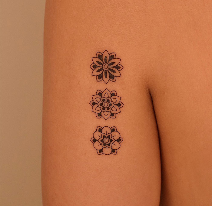 Three small floral tattoos on an arm, showcasing intricate designs that pack a big punch.