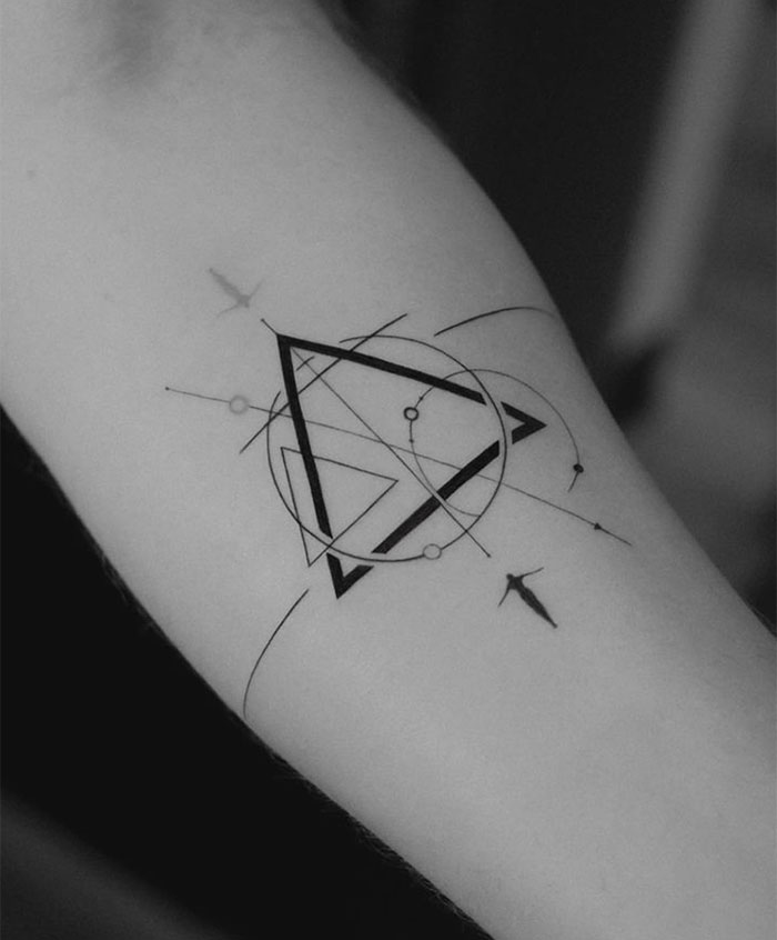 Geometric small tattoo on forearm, featuring intersecting lines, circles, and triangles, showcasing minimalist design.