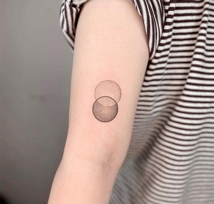 Minimalist small tattoo of overlapping circles on an arm.