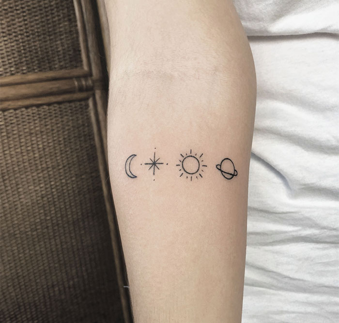 Small tattoo of moon, star, sun, and planet on forearm.