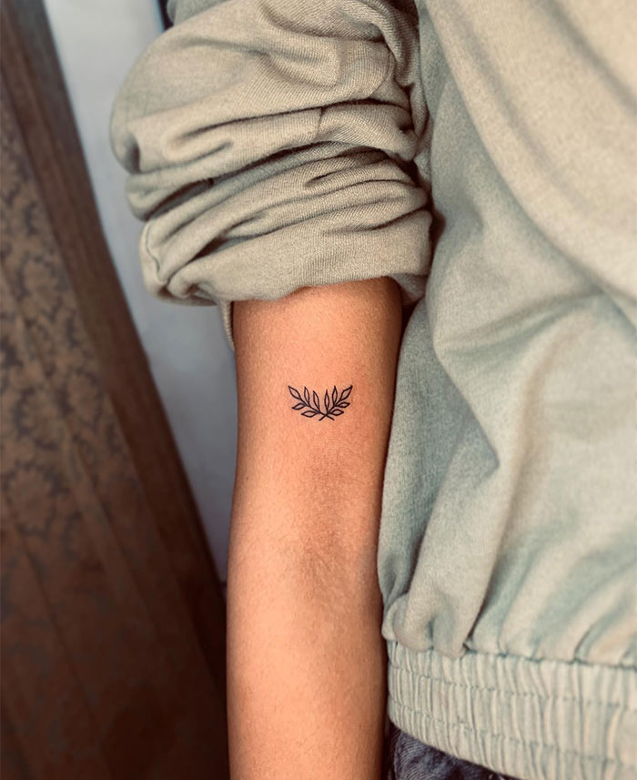 Minimalist small tattoo of leaves on forearm, showcasing a stylish design with big impact.