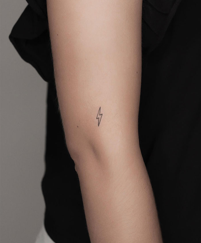 Small tattoo of a lightning bolt on an arm, showcasing minimalist design.