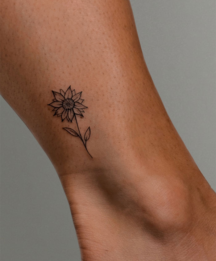 Small tattoo of a sunflower on an ankle, showcasing simple and elegant design.