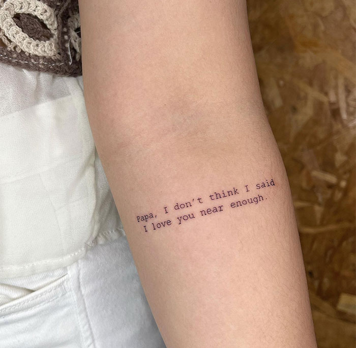 Small tattoo reading "Papa, I don’t think I said I love you near enough" on forearm.
